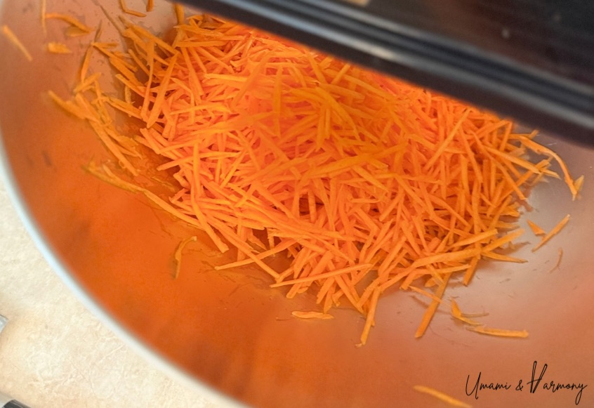 More julienned carrots added to the mixing bowl for carrot râpée salad