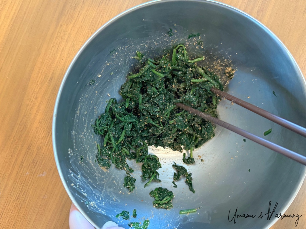 Spinach tossed with ground sesame in a mixing bowl