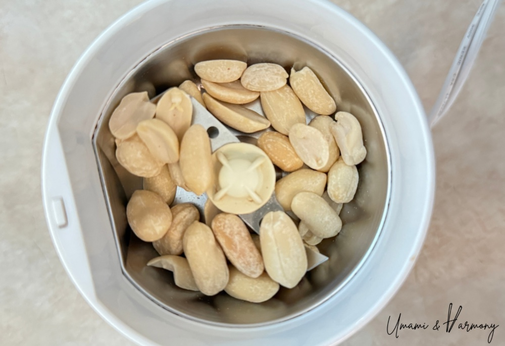Whole peanuts in a food grinder before crushing.