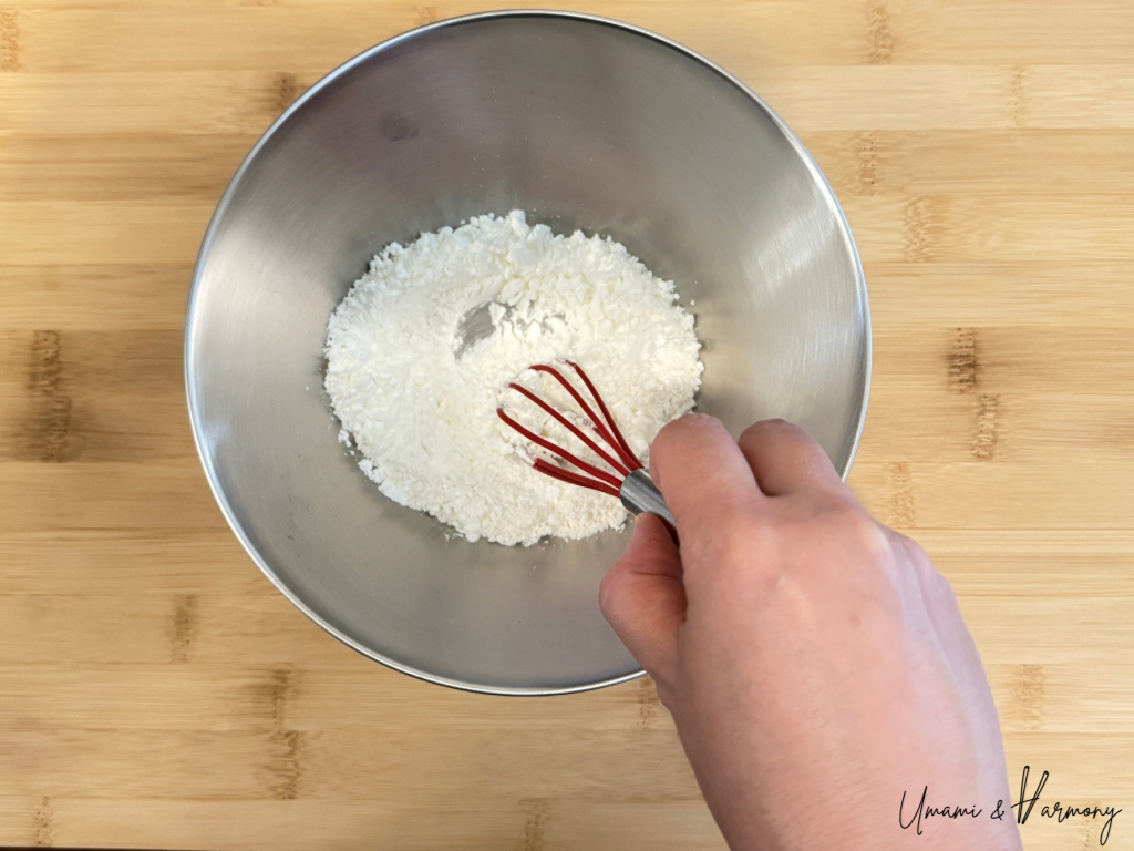 Cornstarch and flour combined in a small bowl with a whisk for karaage coating