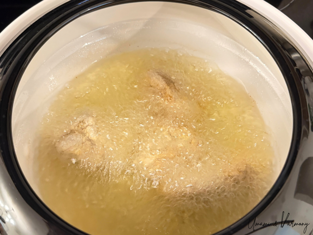 Chicken pieces frying in hot oil in a pot