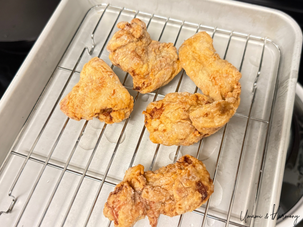 Light golden fried chicken resting on a wire rack.