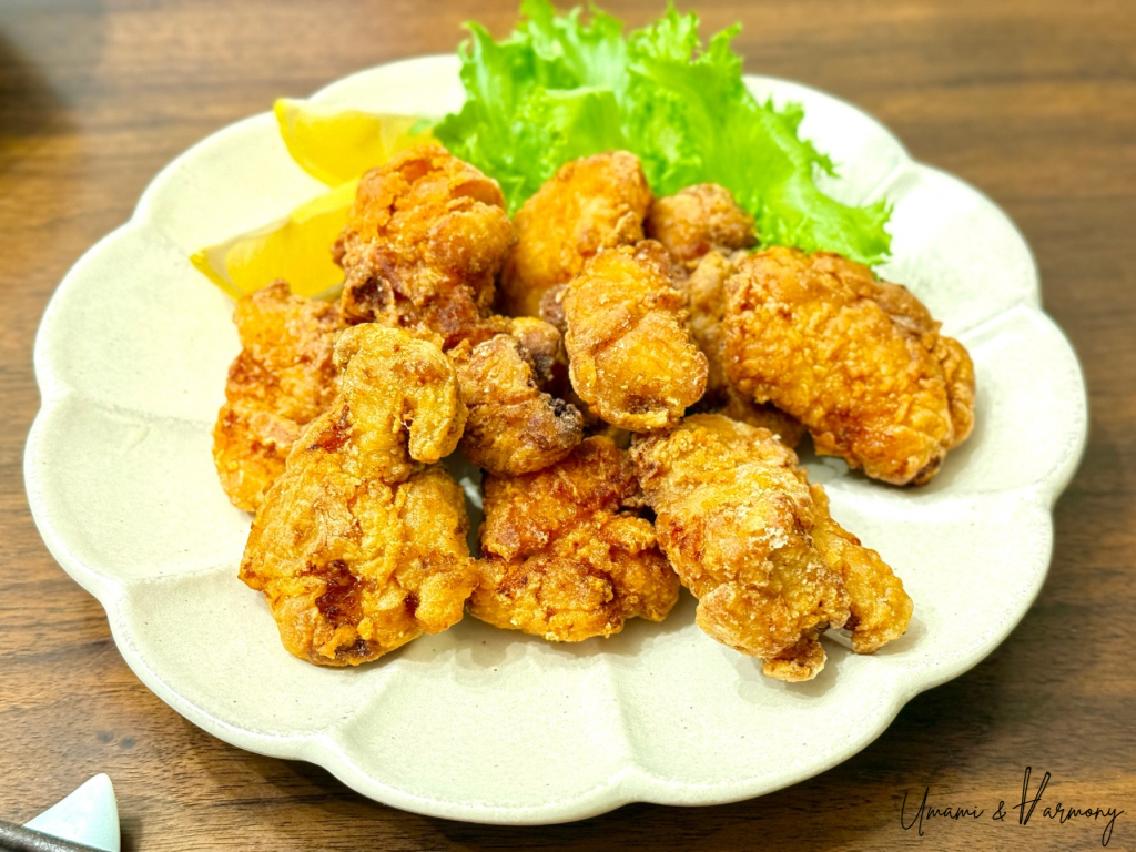Karrage (Japanese fried chicken) served on a plate with lemon wedges and greens. 