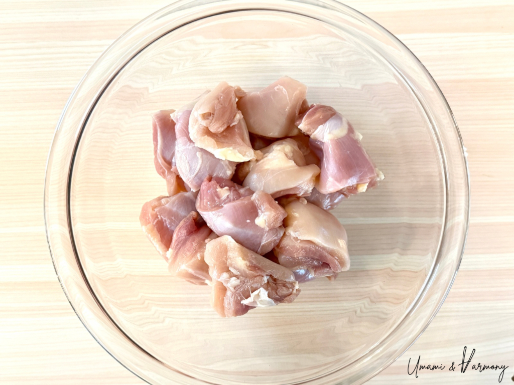 Cut chicken thighs placed in a glass mixing bowl