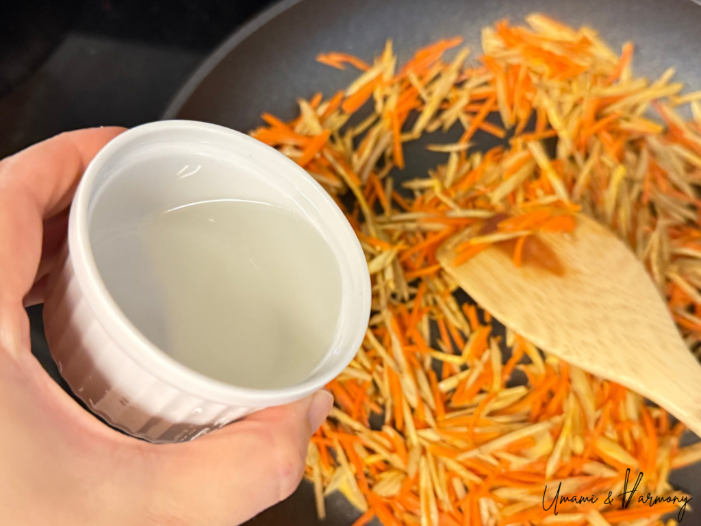 Sake added to the stir-fried vegetables in a pan
