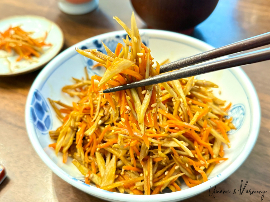 Kinpira Gobo served on a plate with chopsticks picking up a small bite