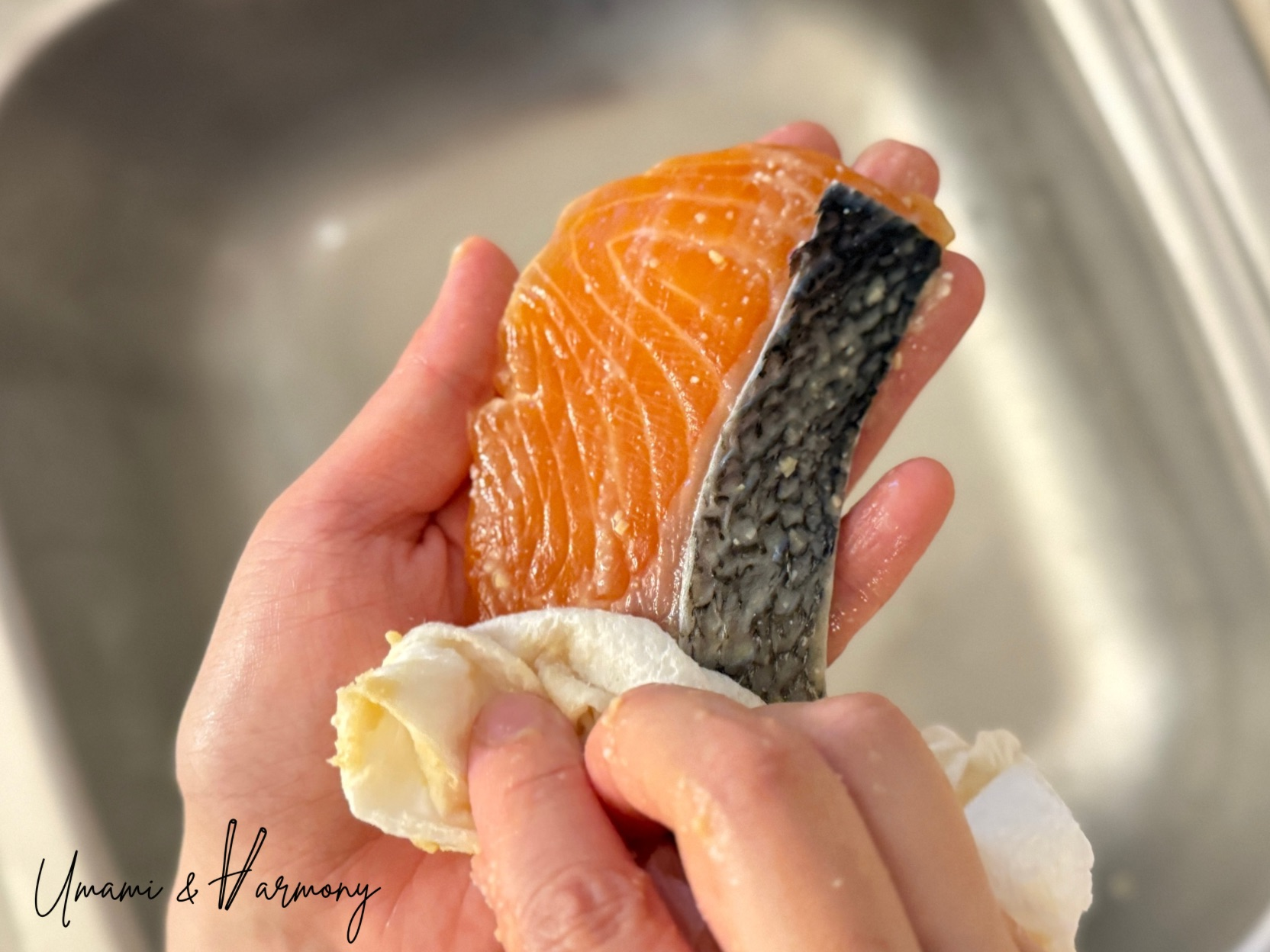Wiping excess miso marinade off salmon fillet with kitchen paper