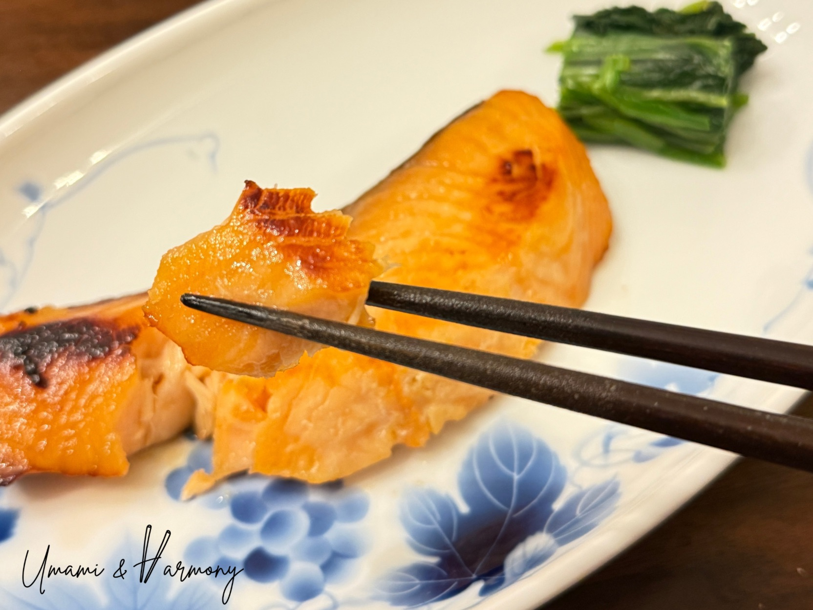 Baked miso salmon served in a dish with chopsticks picking up a piece