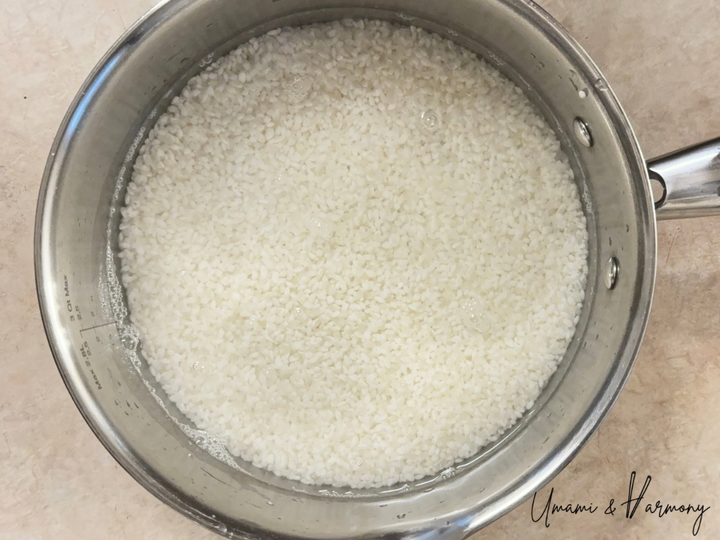 Sushi rice soaking in water in a pot before cooking