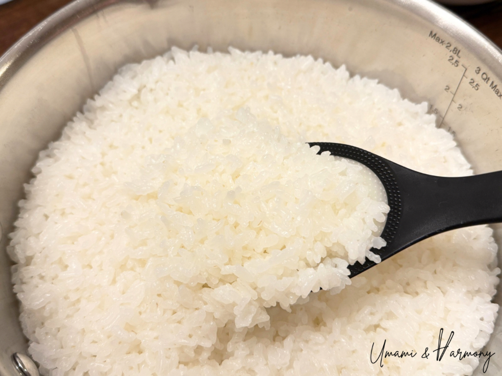 Fluffing cooked sushi rice with a rice paddle