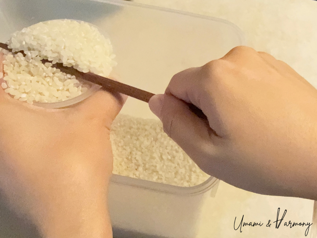Measuring sushi rice with a rice measuring cup and chopstick