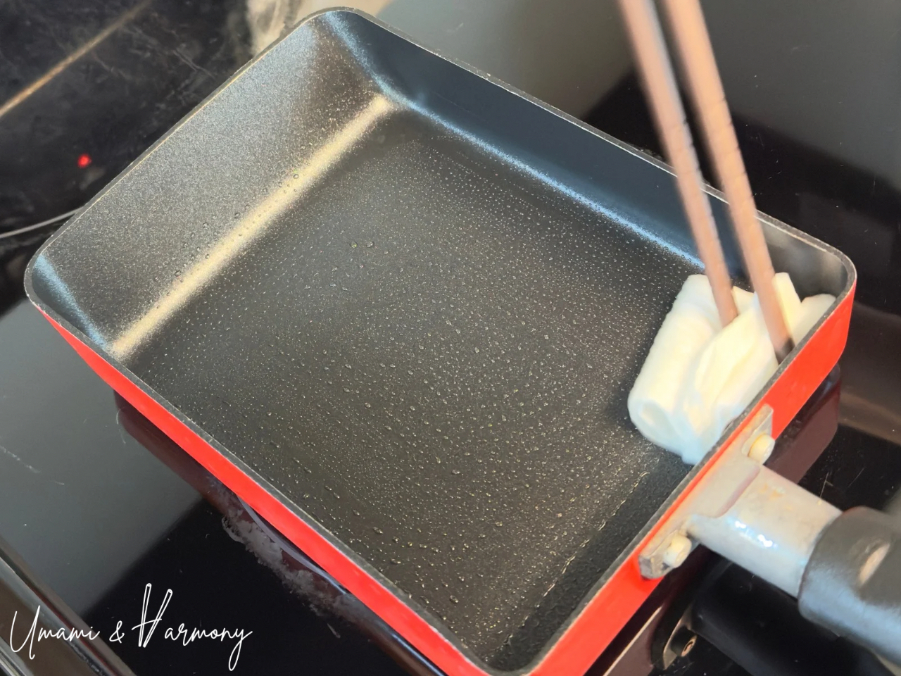 Greasing a tamagoyaki pan with folded kitchen paper