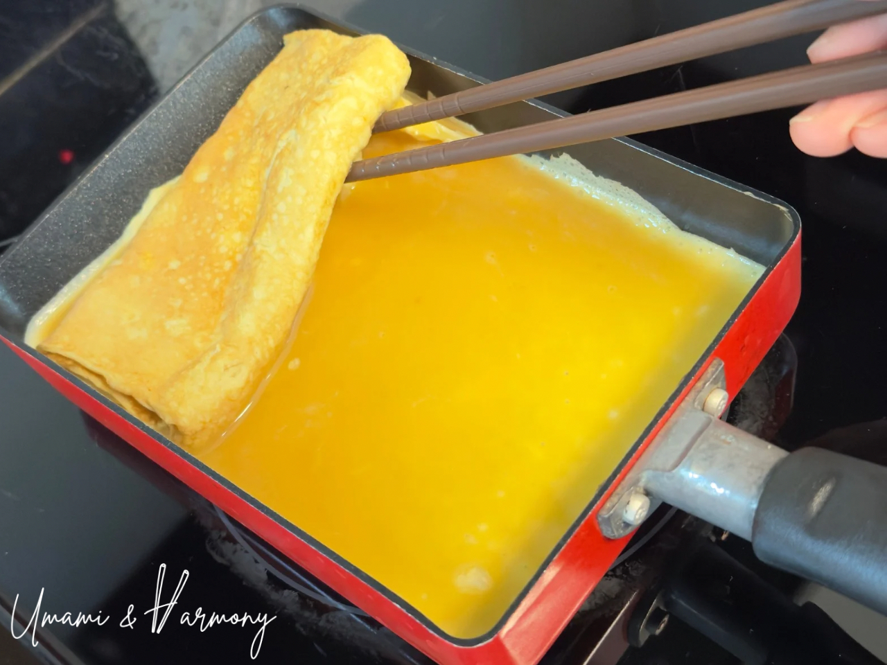 Fresh egg mixture flowing under rolled tamagoyaki