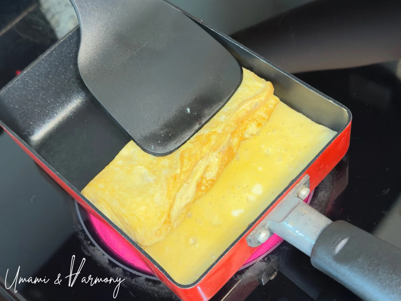 Rolling tamagoyaki second layer with a spatula