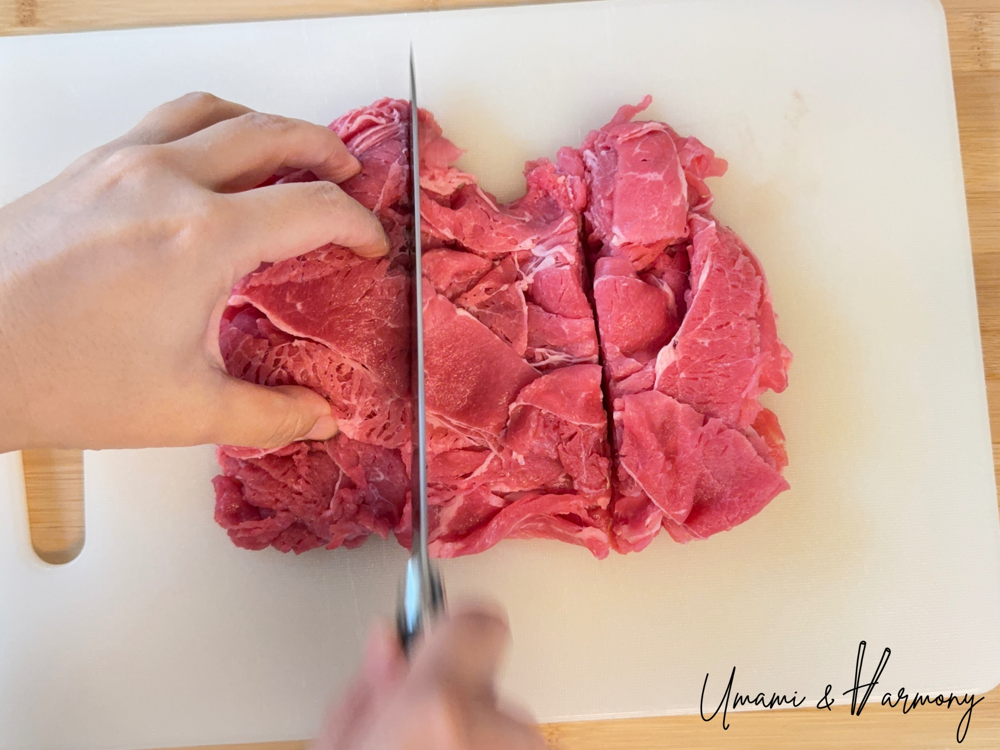Cutting a chunk of shaved beef steak into smaller pieces