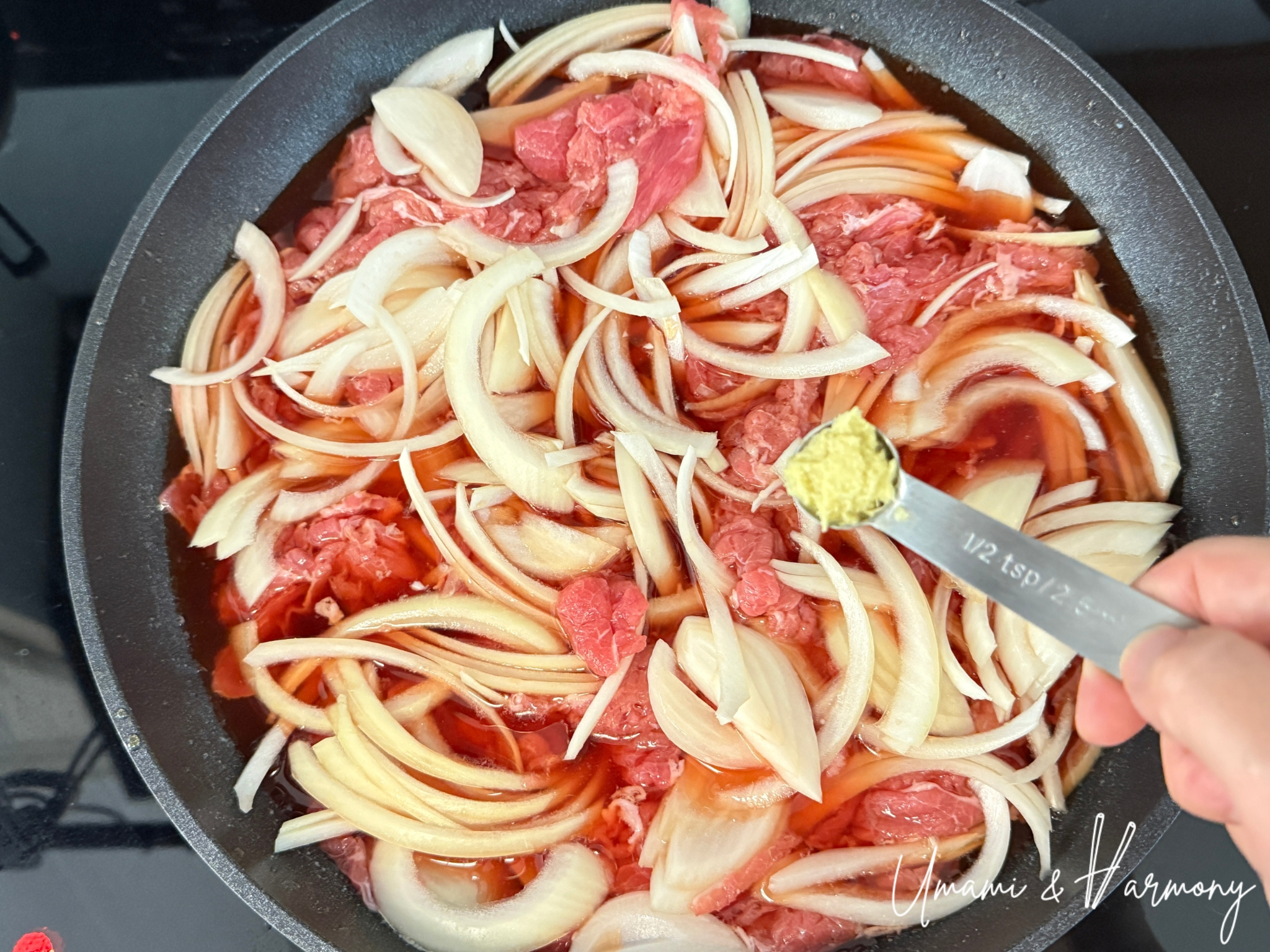 Adding sliced onion and grated ginger on top of the beef