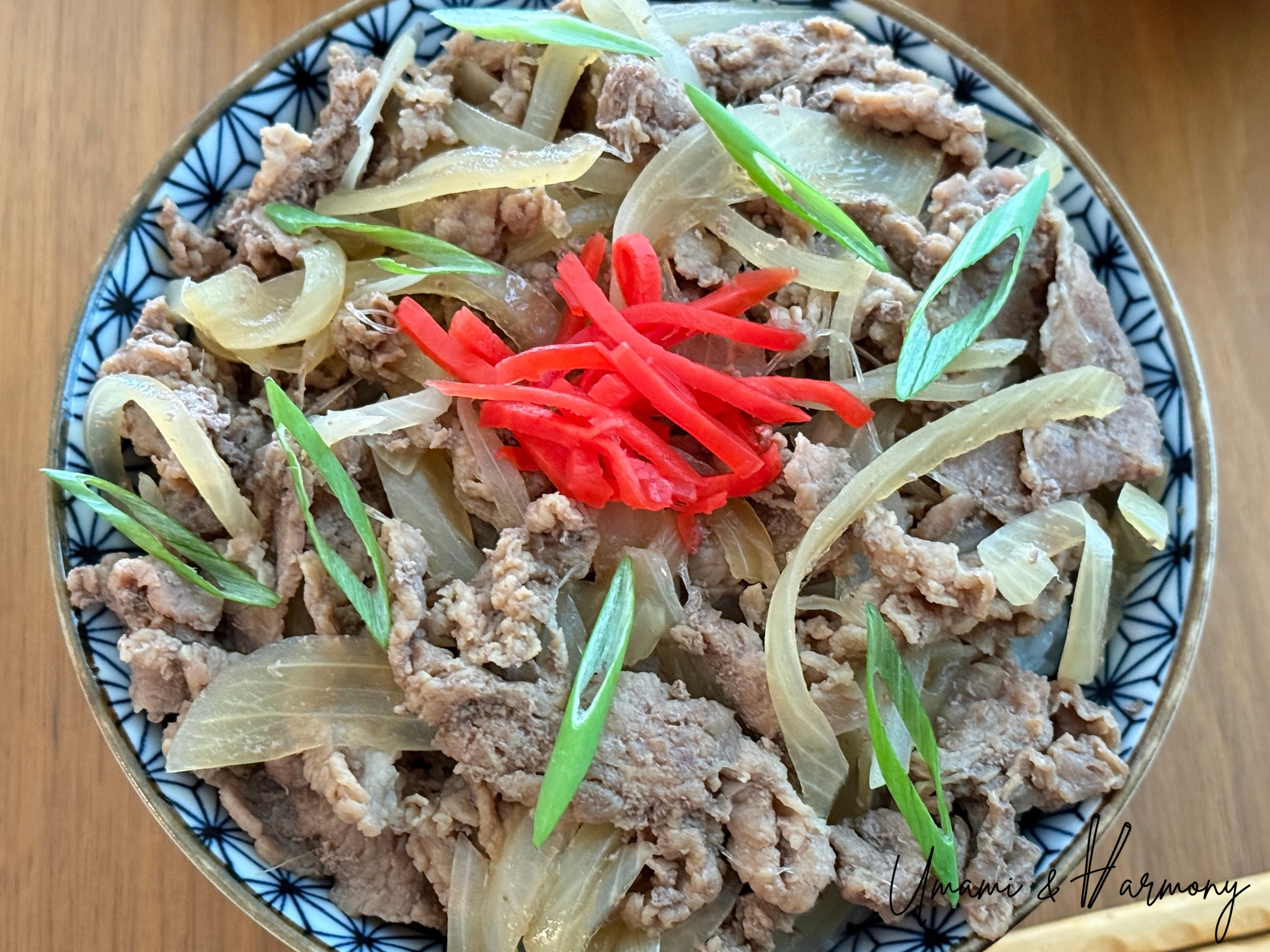 Gyudon ready to serve, garnished with green onion and pickled red ginger