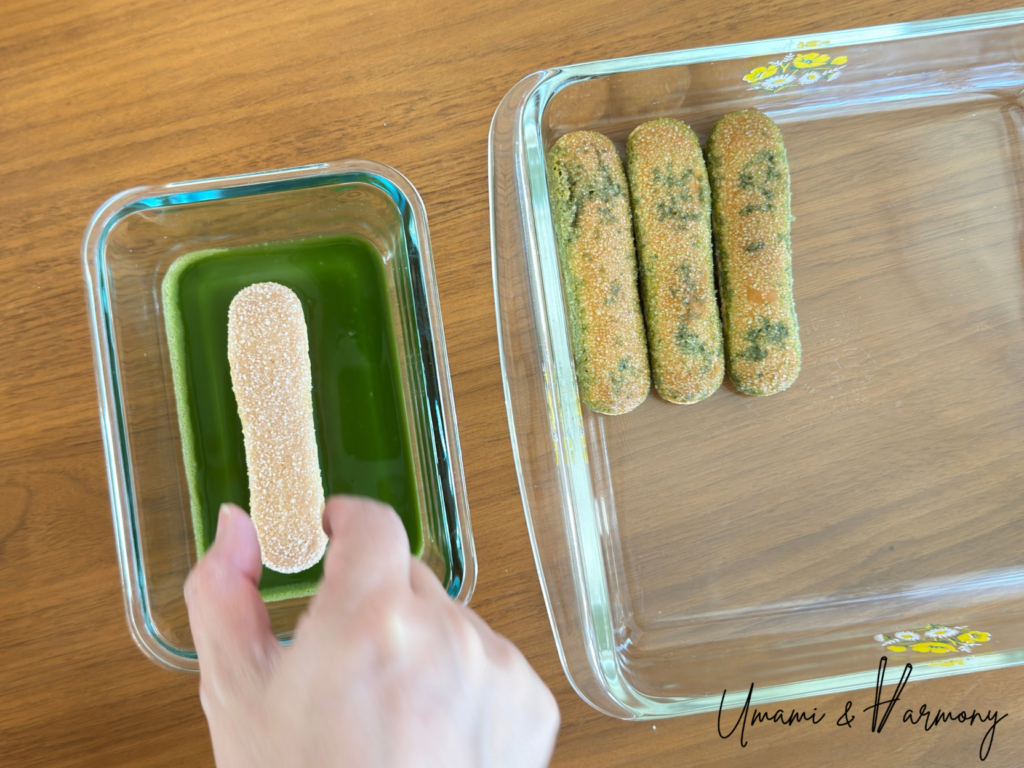 Dipping ladyfinger into matcha mixture and placing it on the bottom of serving dish