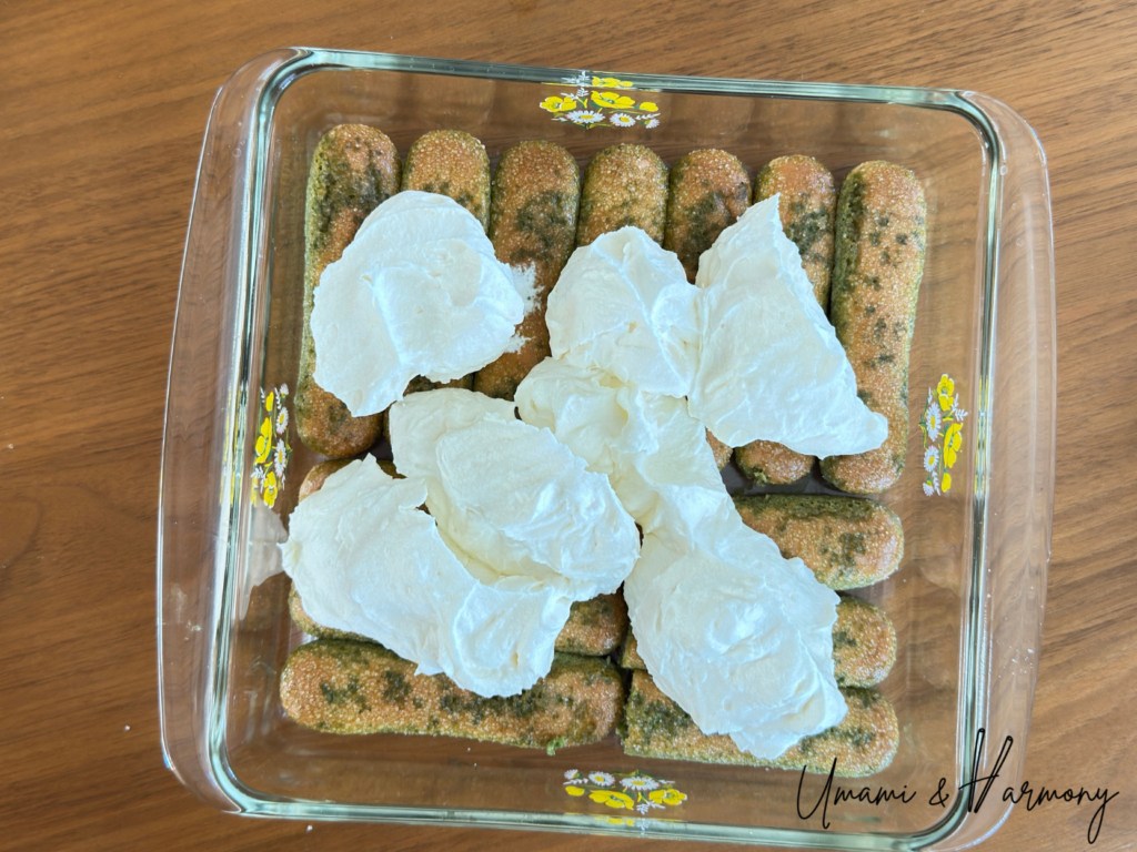 Adding half of the mascarpone cream mixture over the first layer of ladyfingers