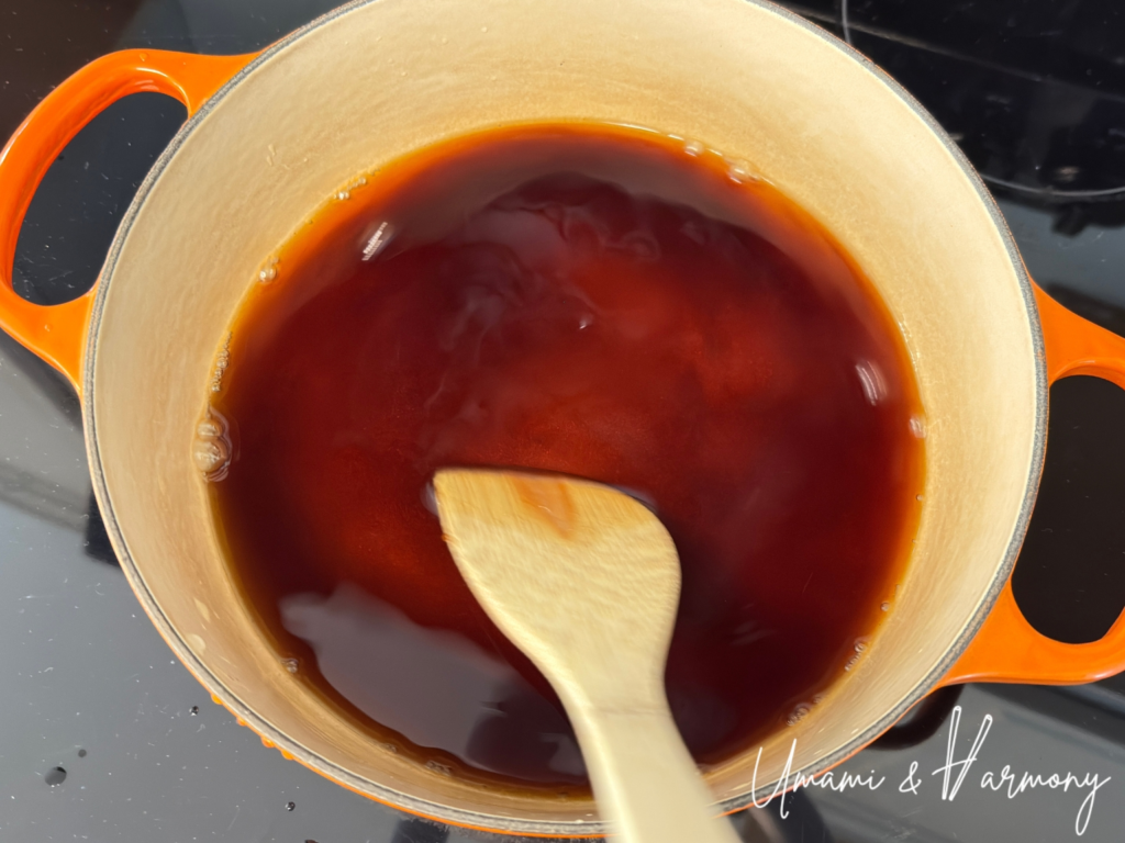 Mixing Nikujaga seasoning with a spatula in a dutch oven