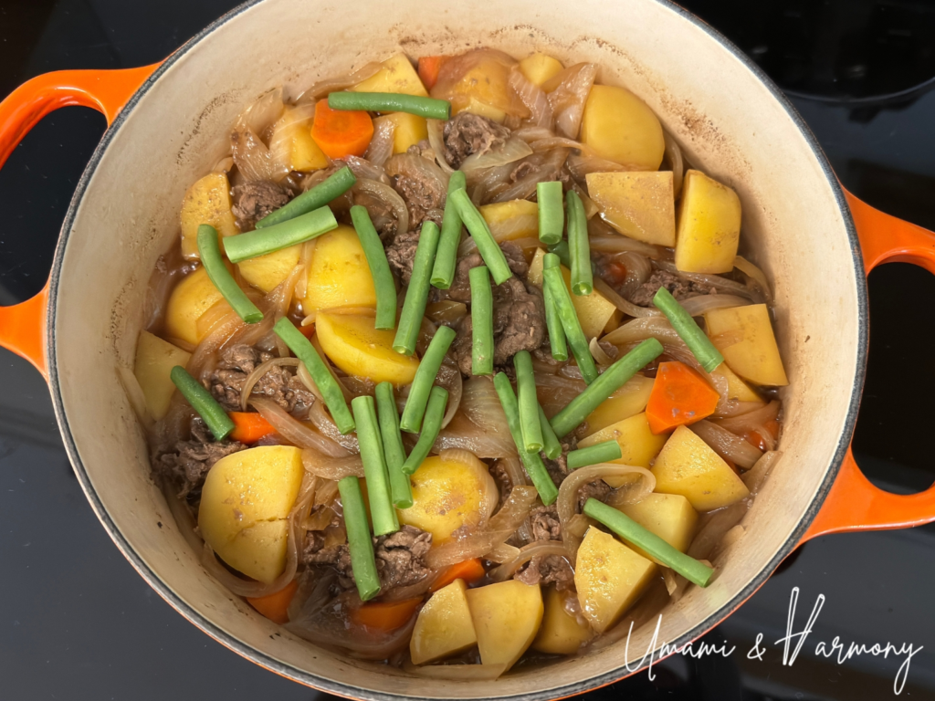 Adding green beans to Nikujaga in the dutch oven