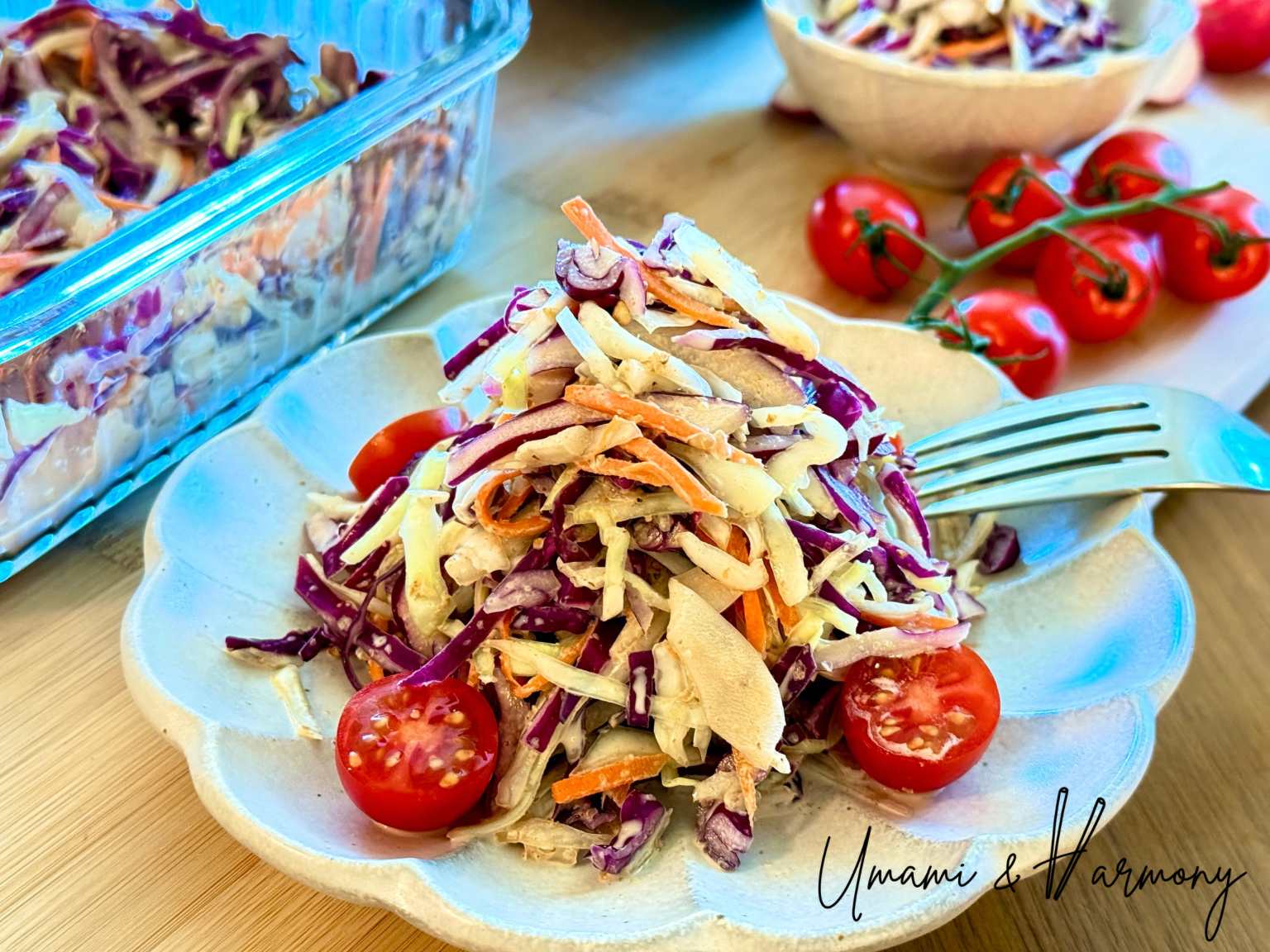 Sesame coleslaw served on a plate with sliced mini tomatoes