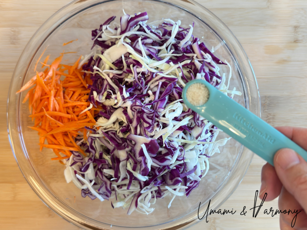 Sea salt being sprinkled over shredded vegetables in a bowl