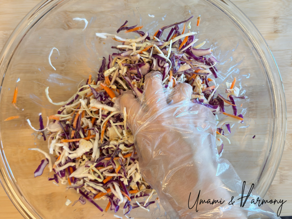 Tossing and mixing coleslaw until evenly coated with sesame dressing