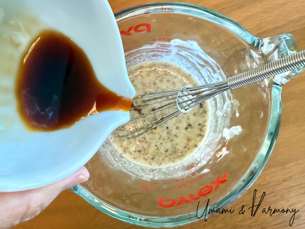Soy sauce being added to a small bowl for sesame dressing