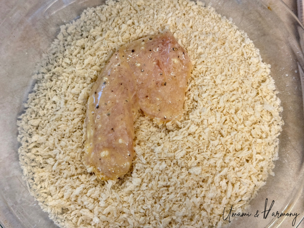 Chicken piece being coated with panko