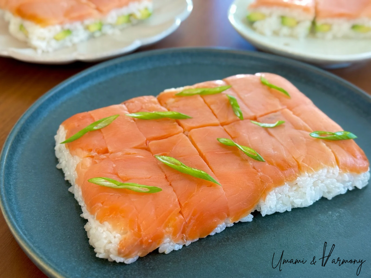 Pressed Smoked Salmon Sushi served on a plate, topped with sliced green onion