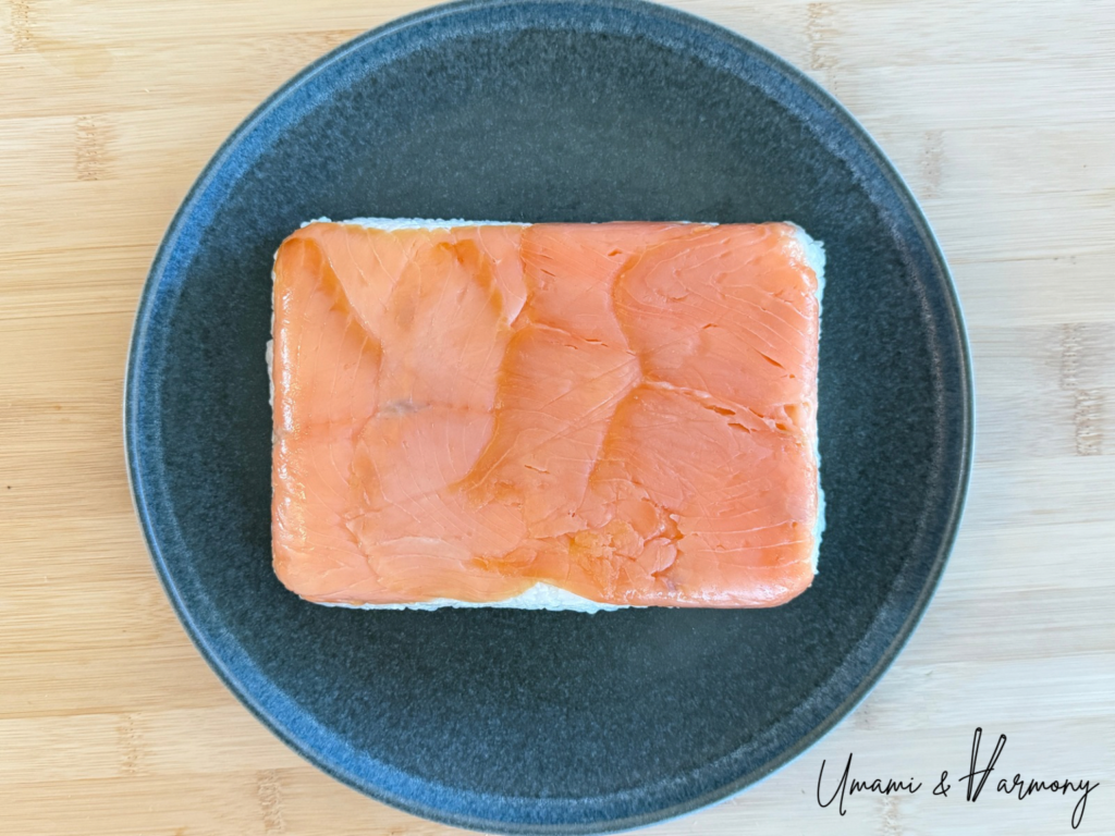 Unwrapped pressed smoked salmon sushi before cutting