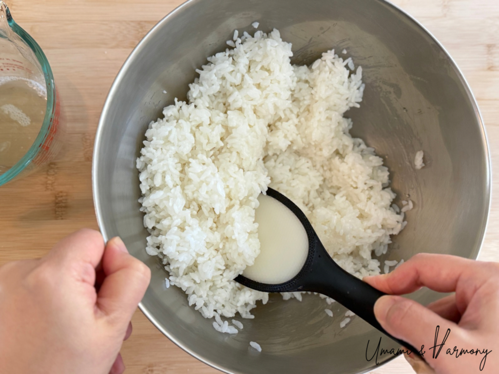 Vinegar mixture poured over white rice and mixed with a rice paddle