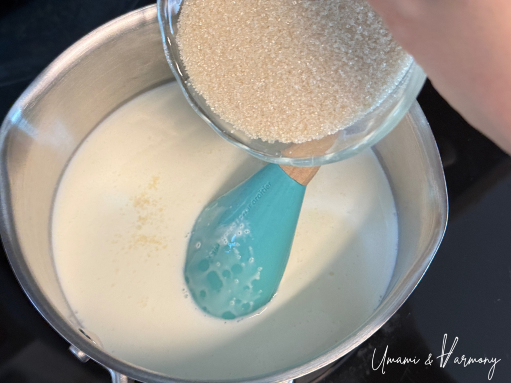 Cane sugar being added to the warm milk and cream mixture