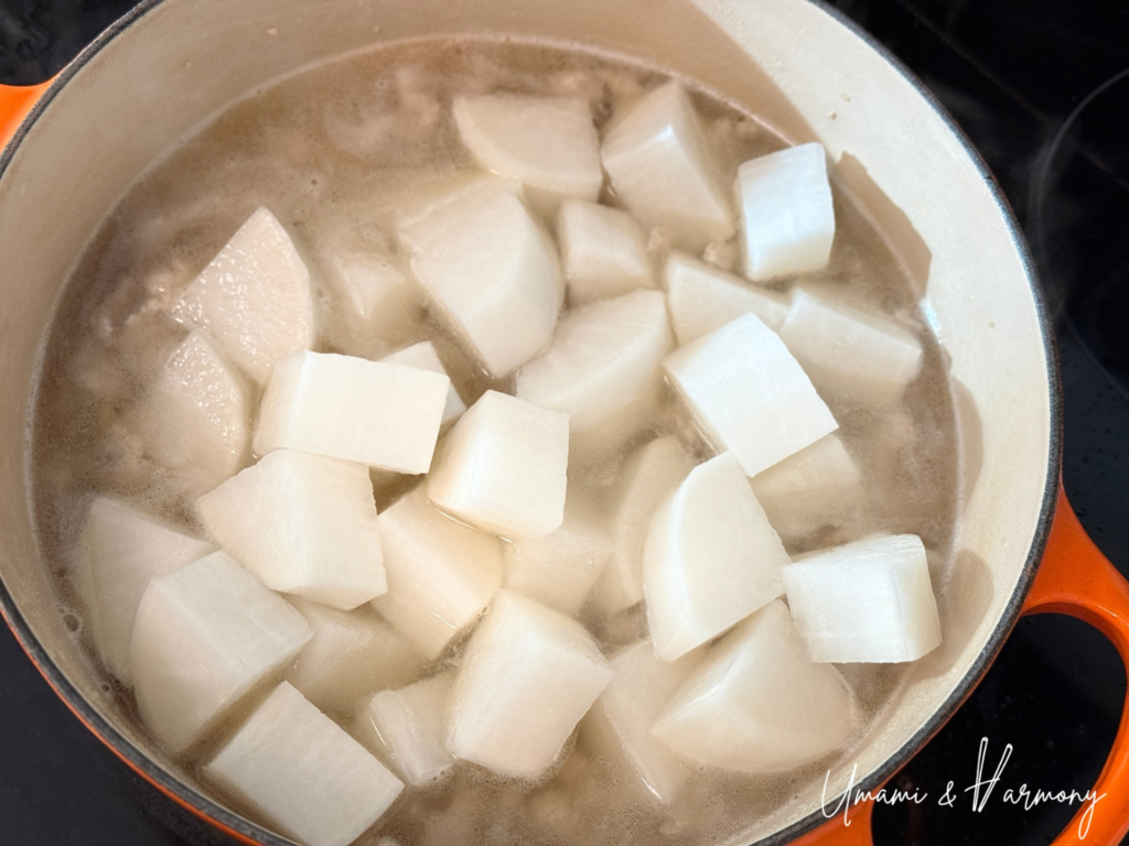 Daikon pieces added to the pot with ground chicken.