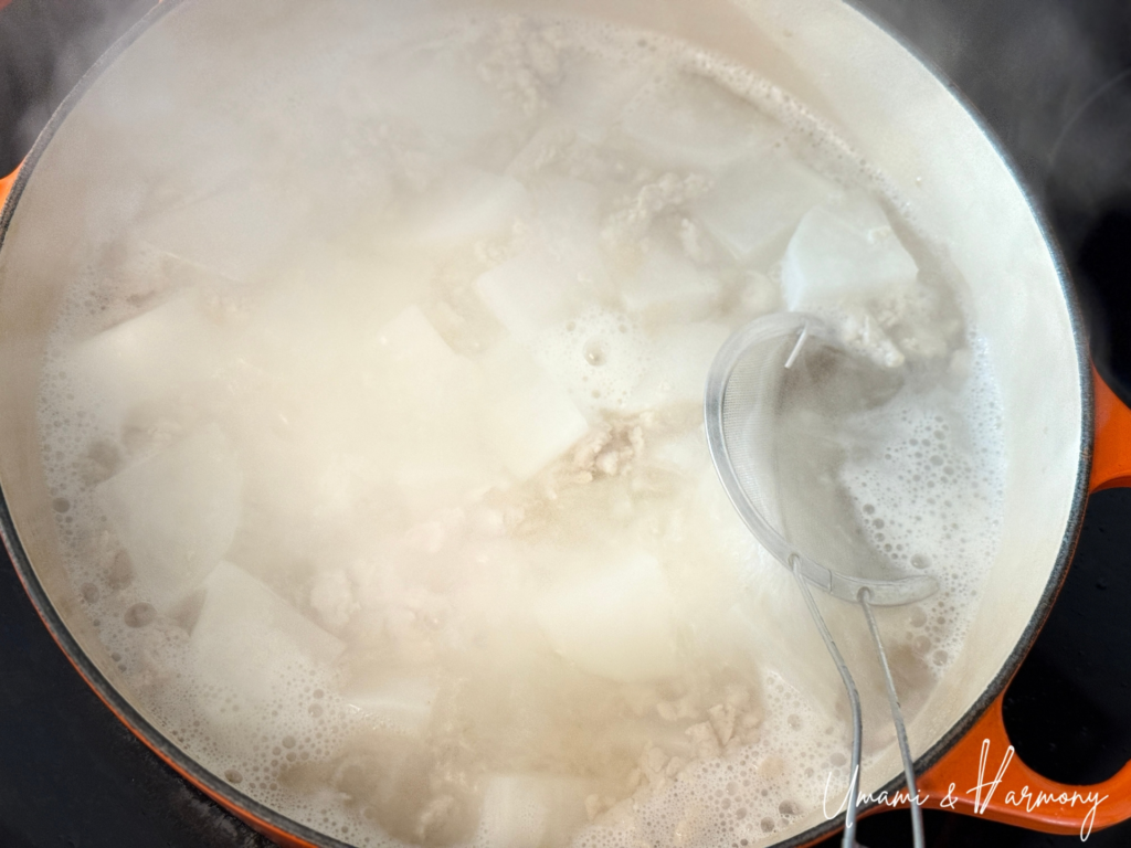 Foam being skimmed from simmering daikon and chicken