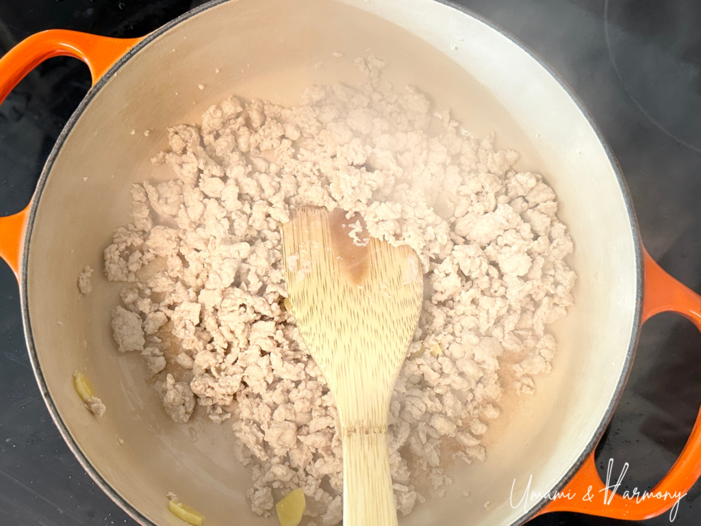 Ground chicken added to a pot and broken into soboro