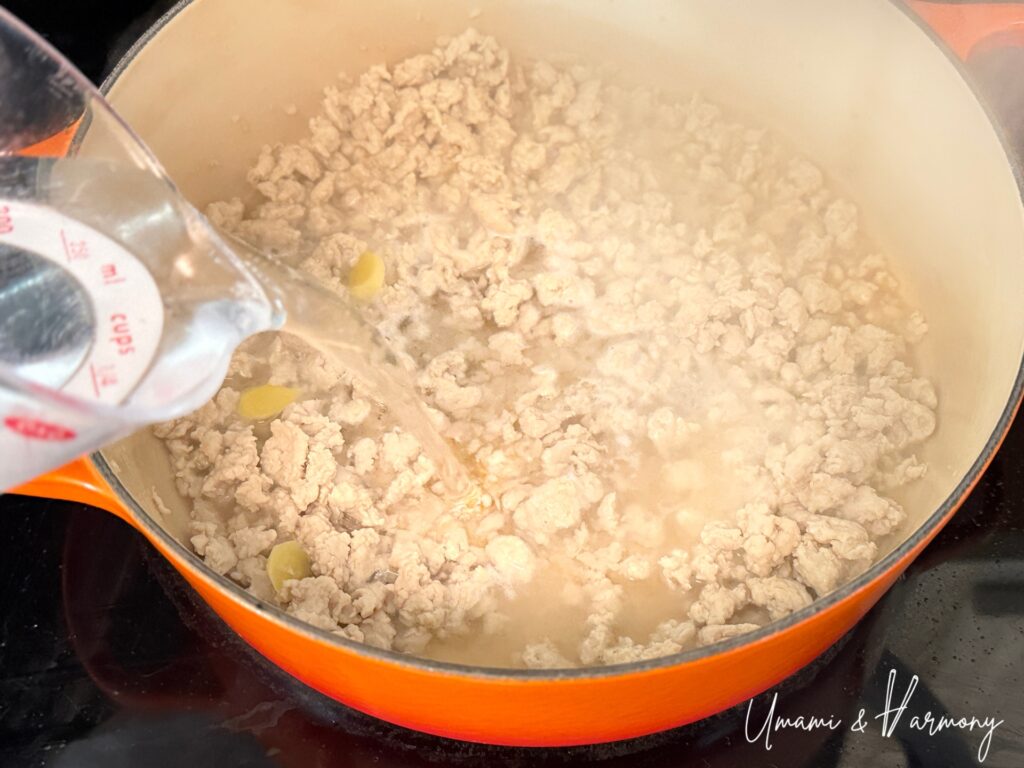 Water being poured into pot with soboro chicken