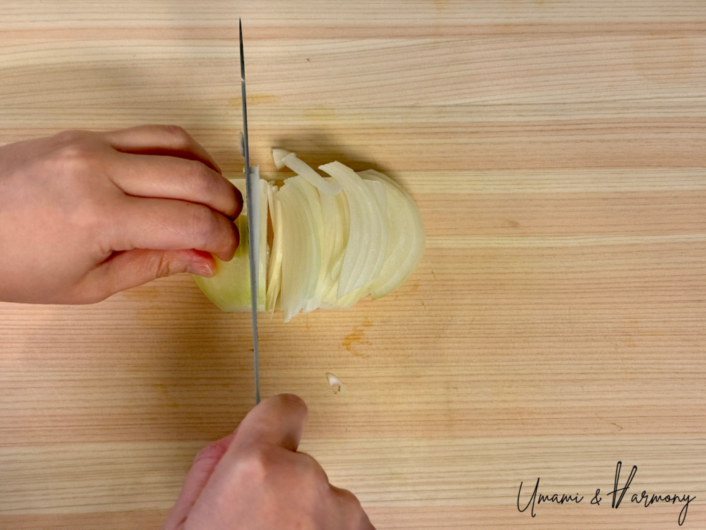 Onion being sliced on a cutting board
