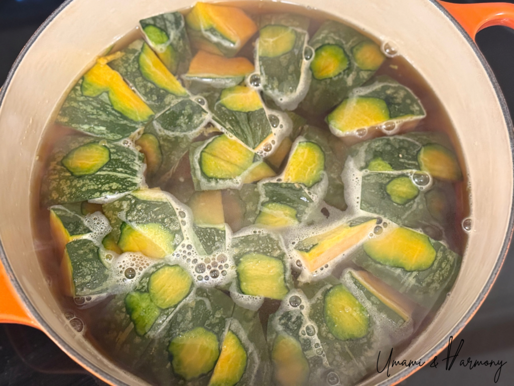 Pot of Kabocha and seasoning coming to a gentle boil on the stove.