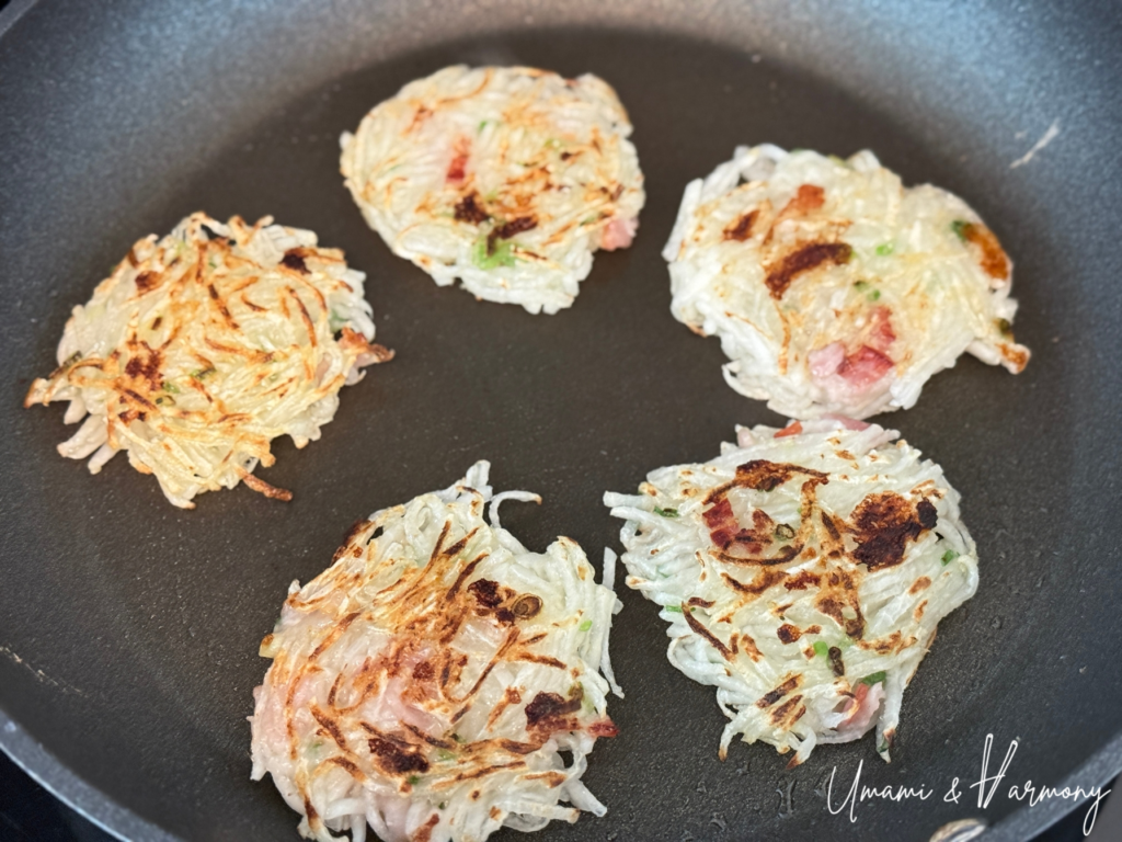 Pan-fried daikon mochi cooking until both sides are golden