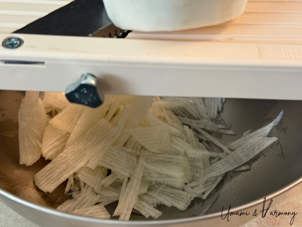Daikon radish being shredded with a slicer