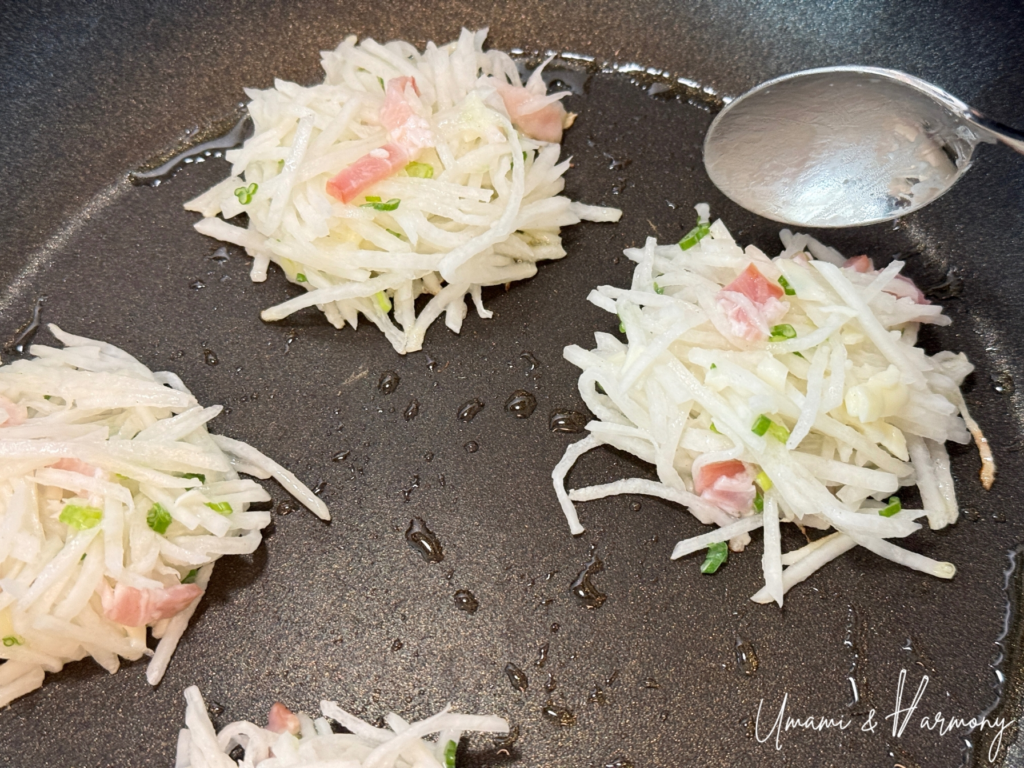 Scoops of daikon mochi mixture placed in a frying pan