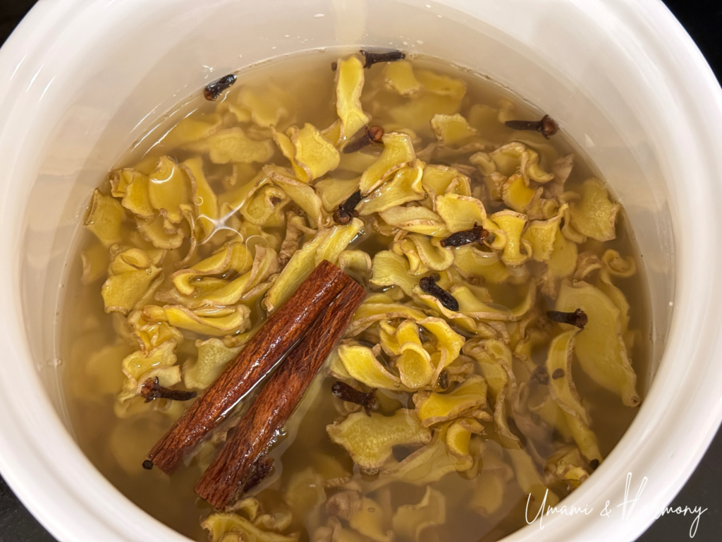 Ginger, sugar, water, and spices simmering in a pot on the stove