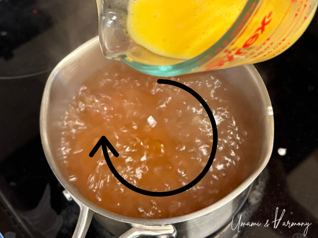 Beaten eggs poured slowly into hot dashi in a circular motion