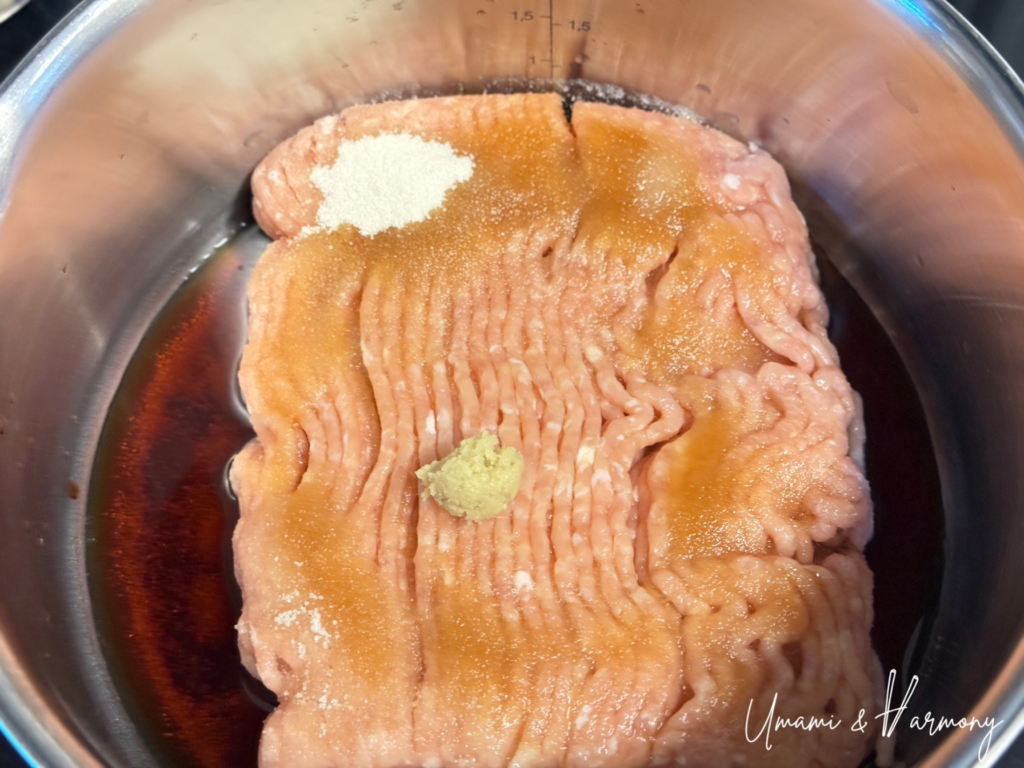 Ground chicken in a pot with sugar, soy sauce, sake, and ground ginger before cooking