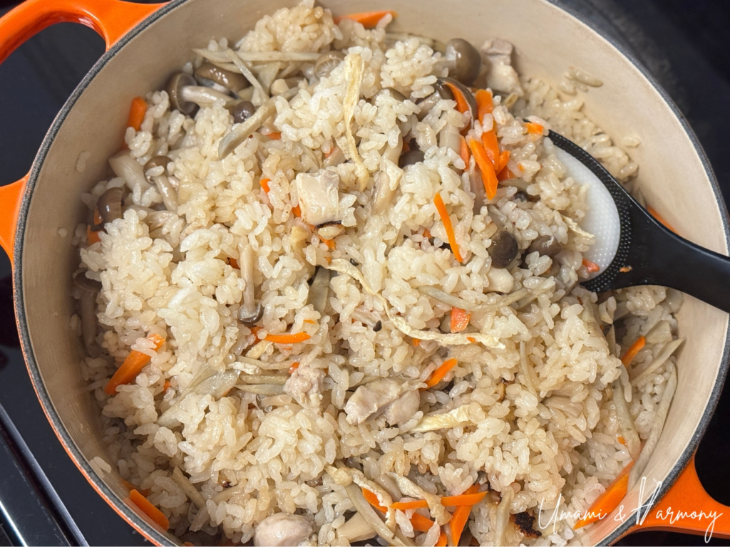 Cooked takikomi gohan being gently fluffed with a rice paddle