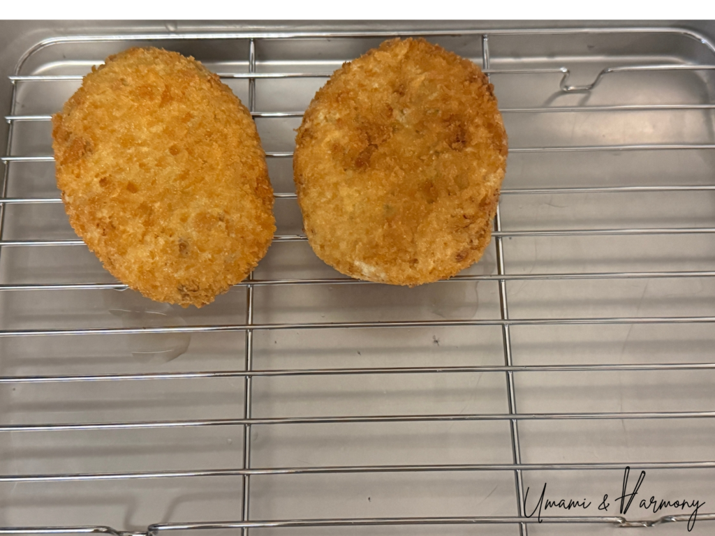 Freshly fried croquettes resting on a wire rack to drain excess oil