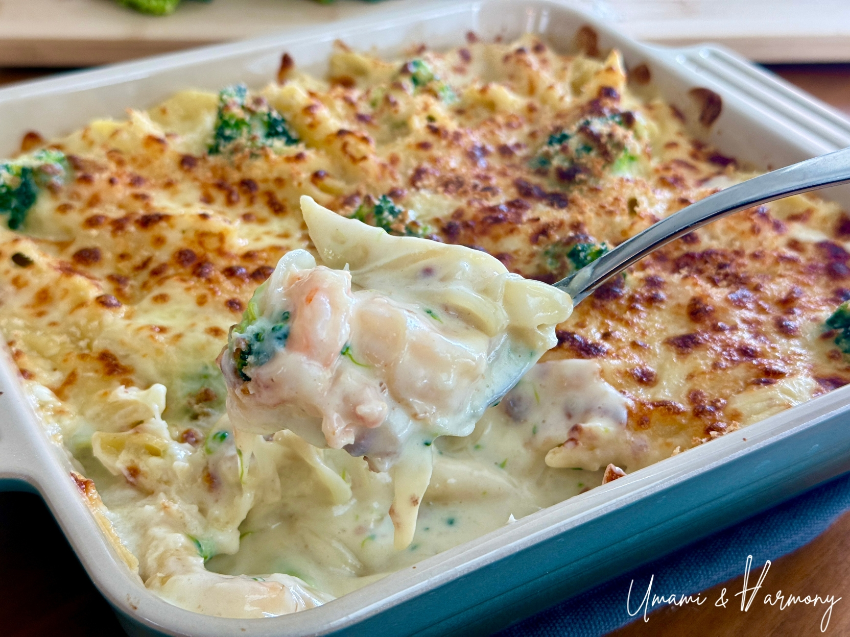 Shrimp macaroni gratin with a crispy golden top being scooped to show the creamy inside