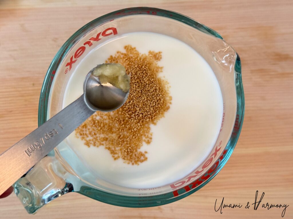 Consommé powder and grated garlic being added to milk